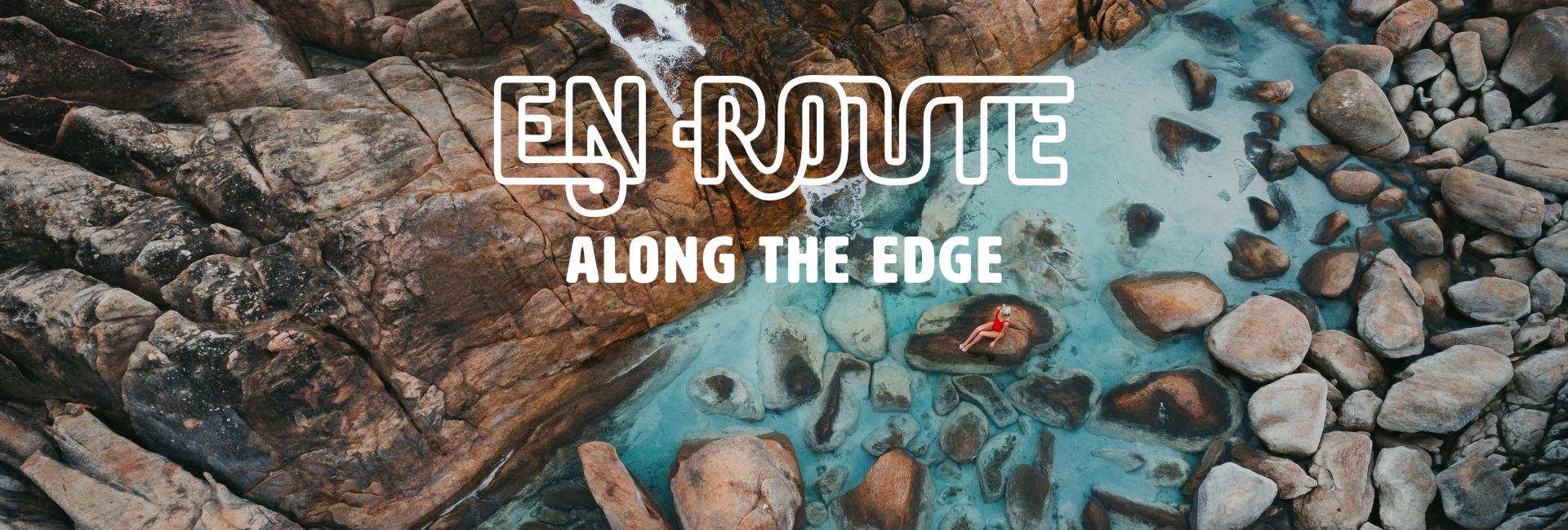 drone shot of a girl on a rock pool with En Route Along The Edge logo 