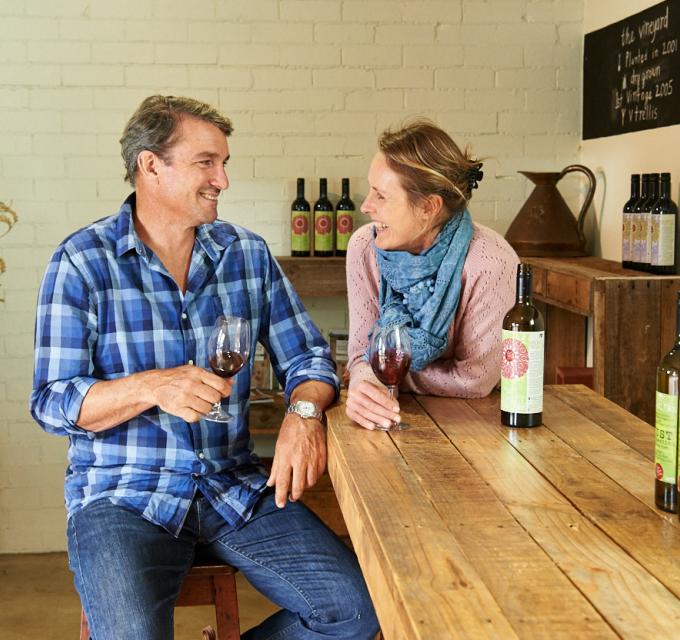Husband and wife share a glass of wine in a cellar door