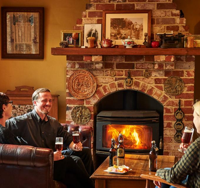 A group of three friends enjoy a beer by a fire in Bridgetowns The Cidery 